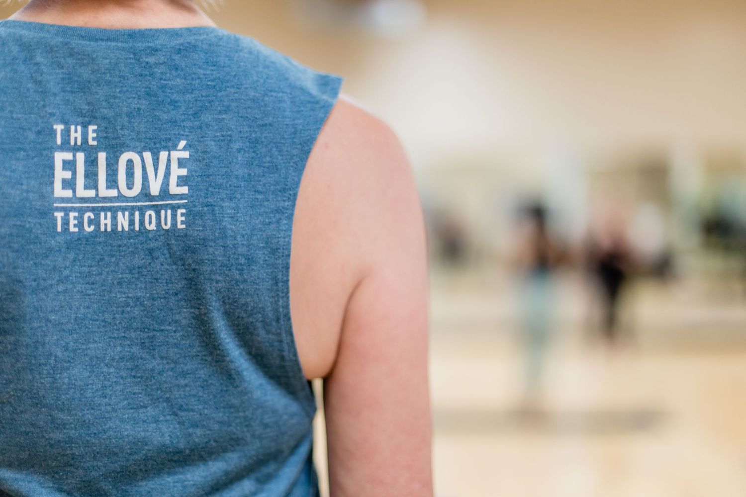 Close-up view of someone wearing a blue sleeveless shirt with 'The Ellove Technique' text on the back.