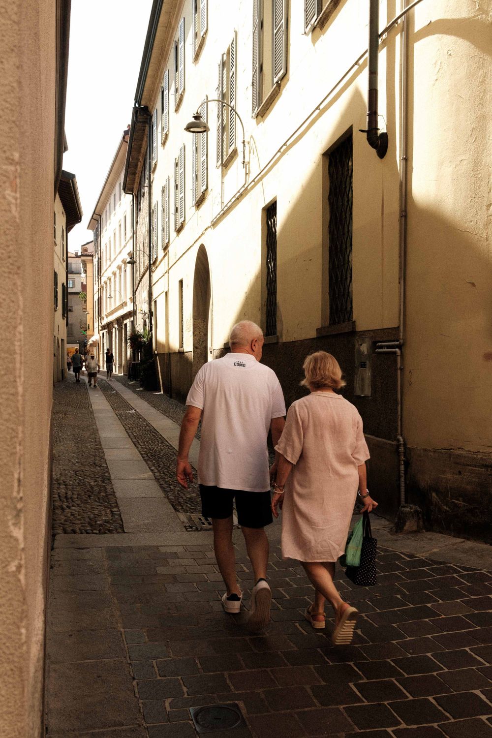 A couple walking together down a narrow cobblestone street in a historic district.