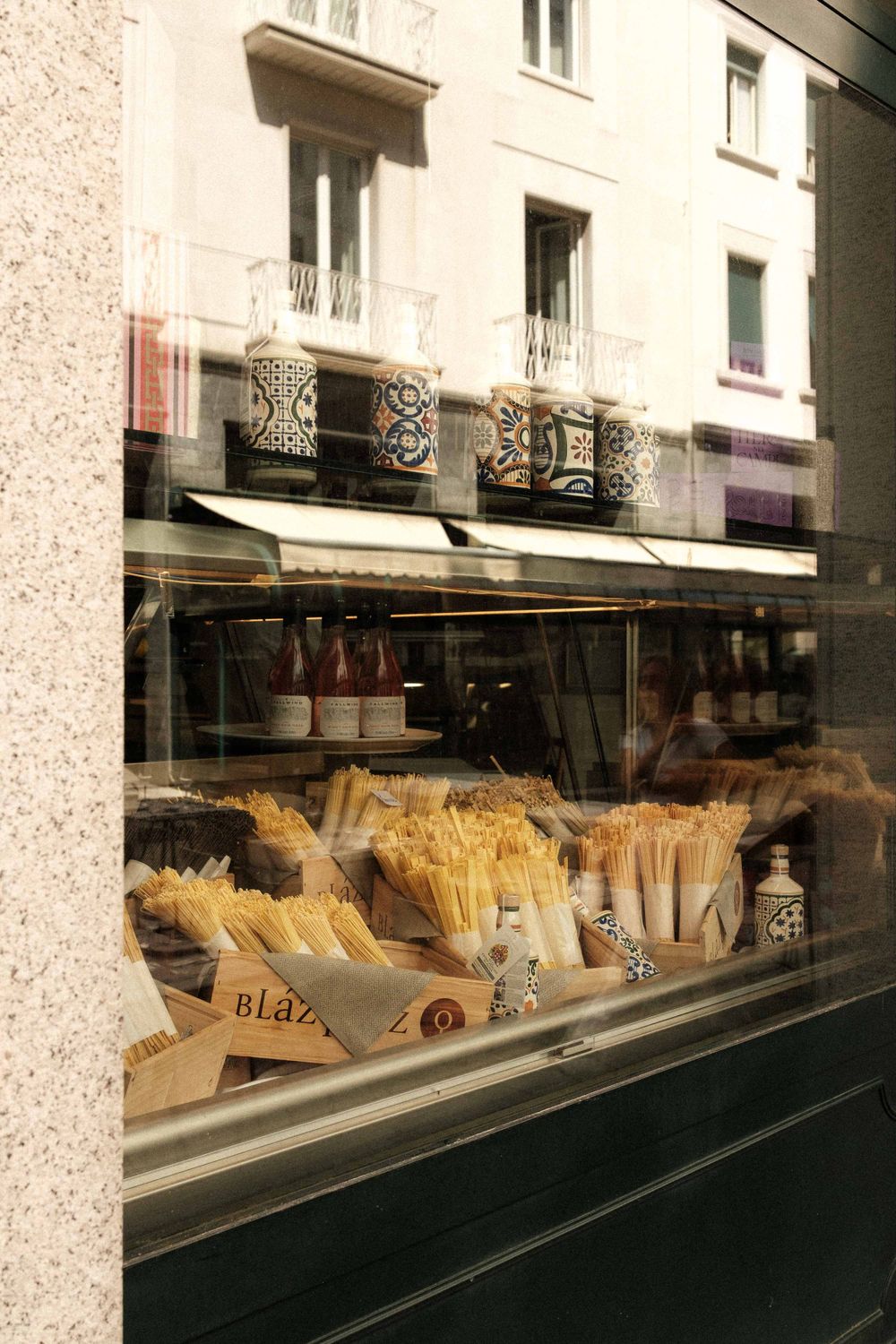 Storefront window display of a pasta shop with various dried pasta varieties neatly arranged.