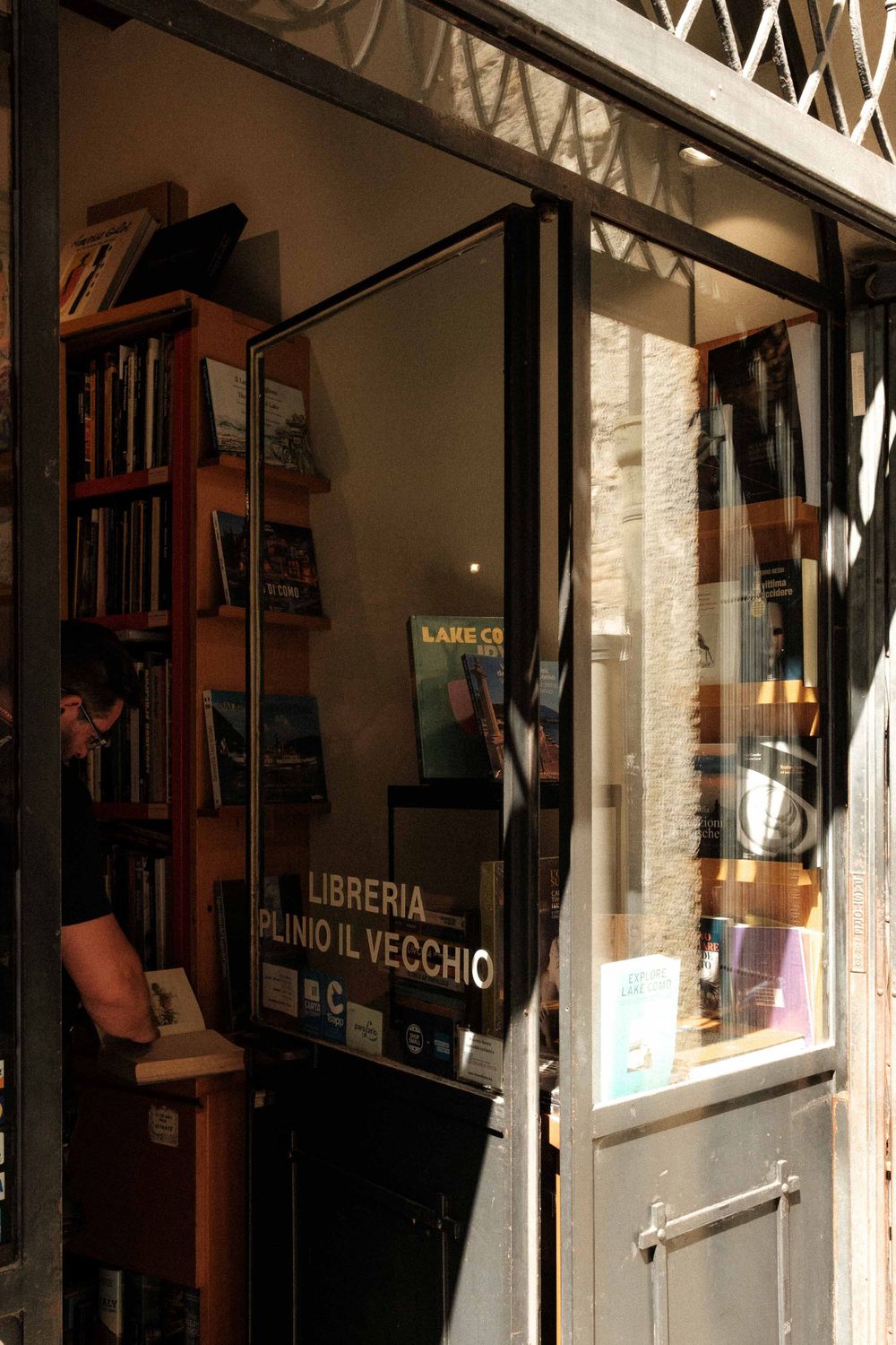 Interior view of an Italian bookstore entrance with wooden shelves and vintage signage.