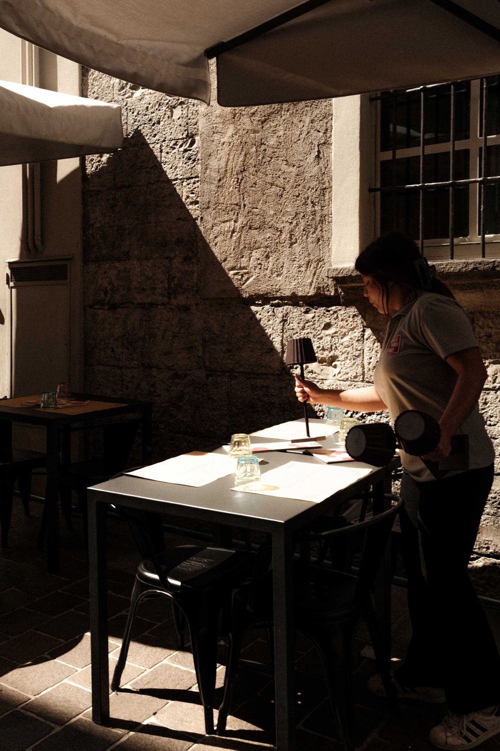 A person working at a desk in dramatic lighting against a textured stone wall.