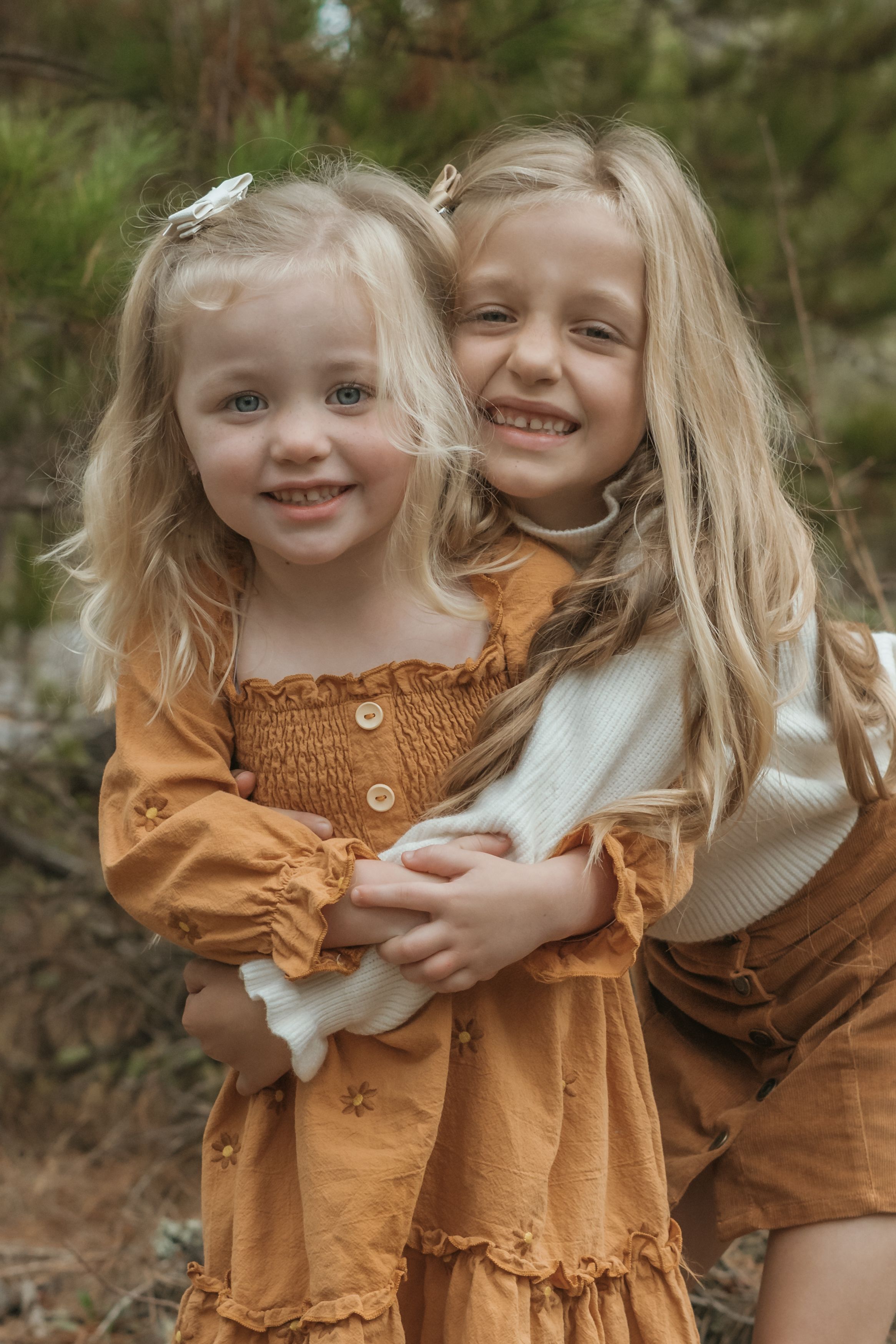 Two young children in brown and white outfits share joyful moments together in an outdoor setting.