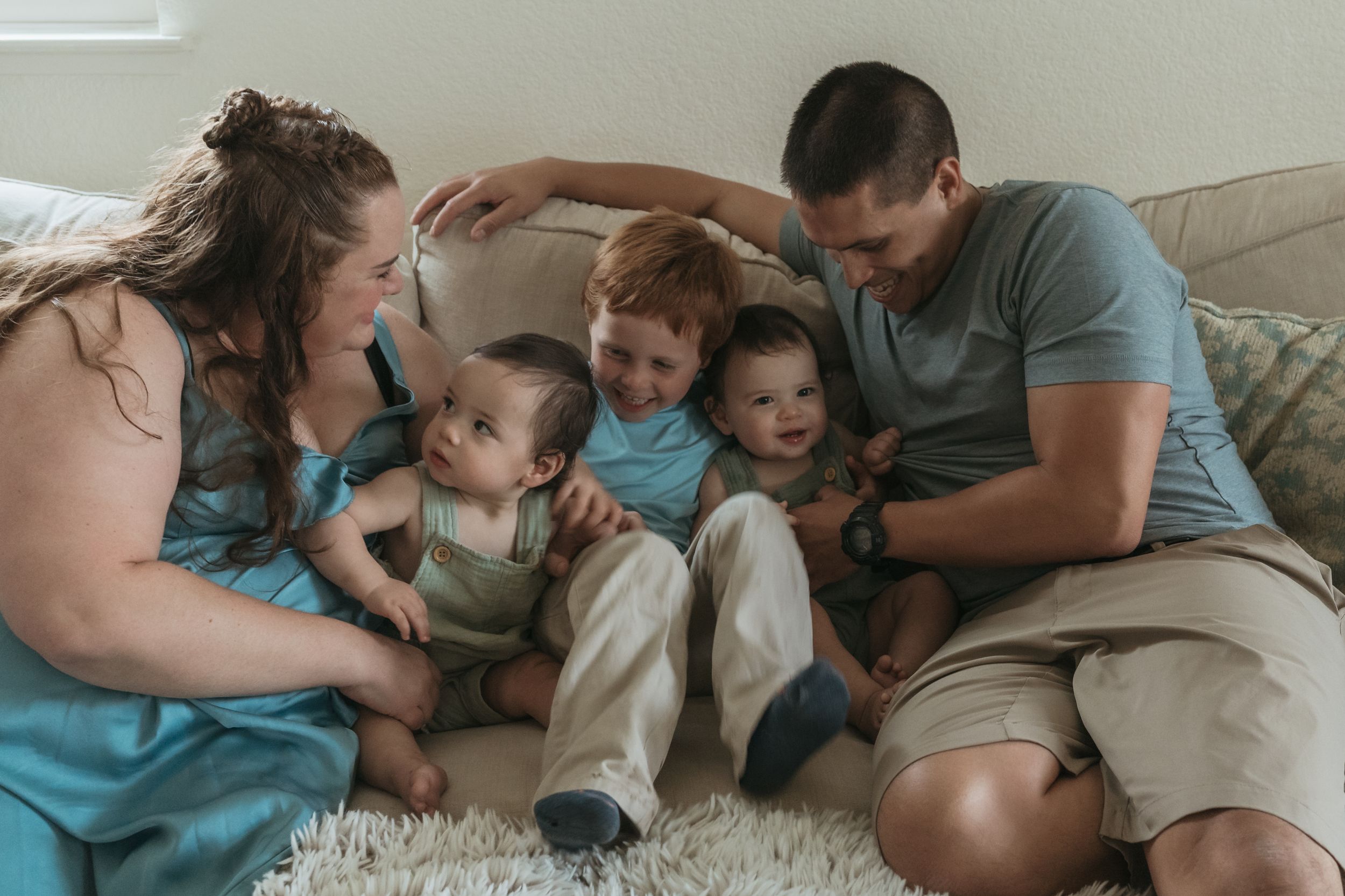 Family lying together on carpet at home sharing tender moments and affectionate interactions.