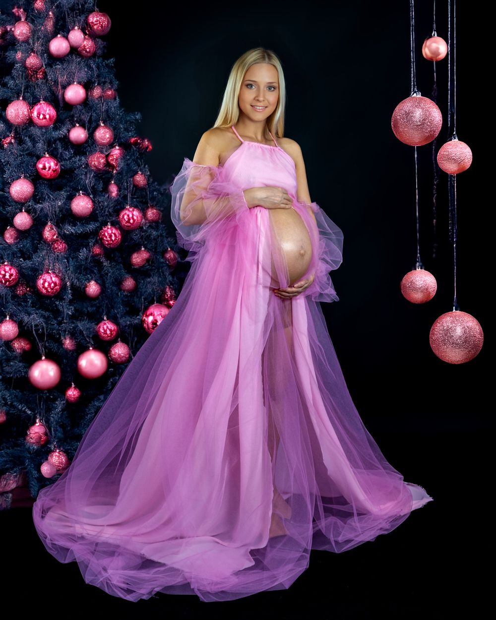 Maternity portrait with pink Christmas decorations and flowing tulle gown.