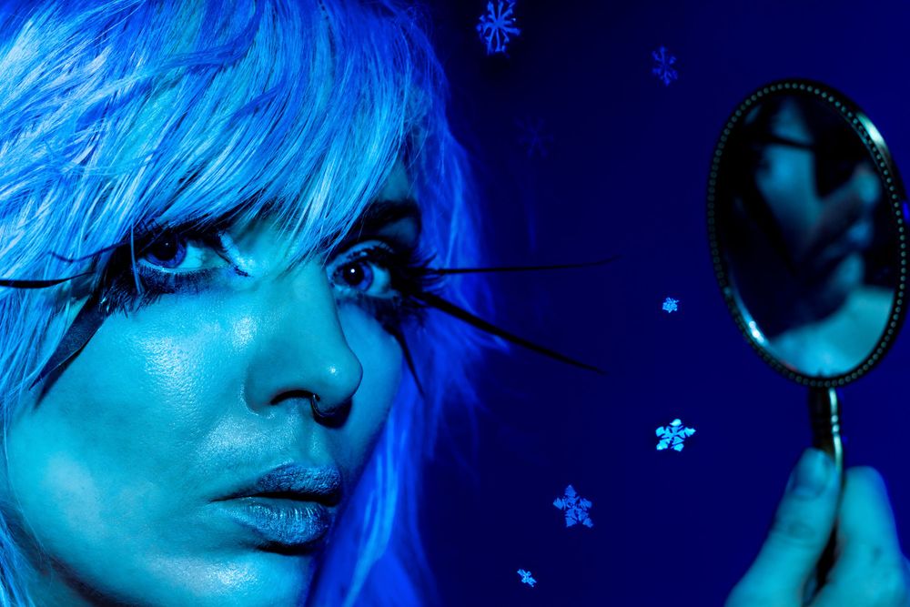 Dreamy blue-toned portrait with hand mirror and star decorations.