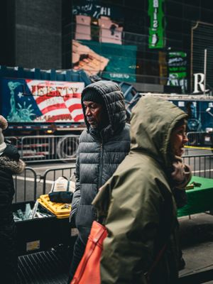 Urban street scene with pedestrians walking past storefronts and yellow taxis.