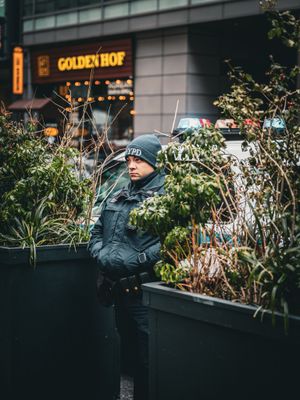 Police officers patrol near planters outside a storefront with Golden Hof signage.