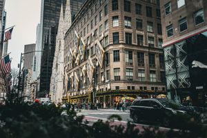 Urban cityscape with classic New York architecture and American flag visible.