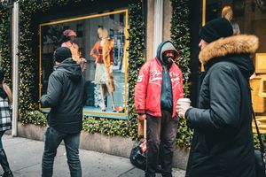 People bundled in winter coats walk along a city sidewalk on a cold day.