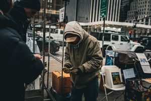 Street vendor cart on a city sidewalk with buildings in the background.