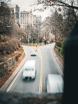 Motion-blurred cars driving on a curved road through an urban area.
