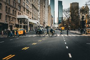 Urban street scene with cyclists, yellow taxis, and tall buildings in New York City.