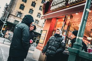 People gathered outside a diner with neon signage on a cold winter evening in the city.