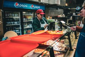 Food vendor cart with Pepsi branding and red awning on city street.