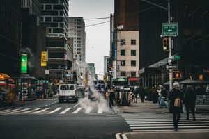 Urban street scene with steam rising from city grates in moody black and white tones.