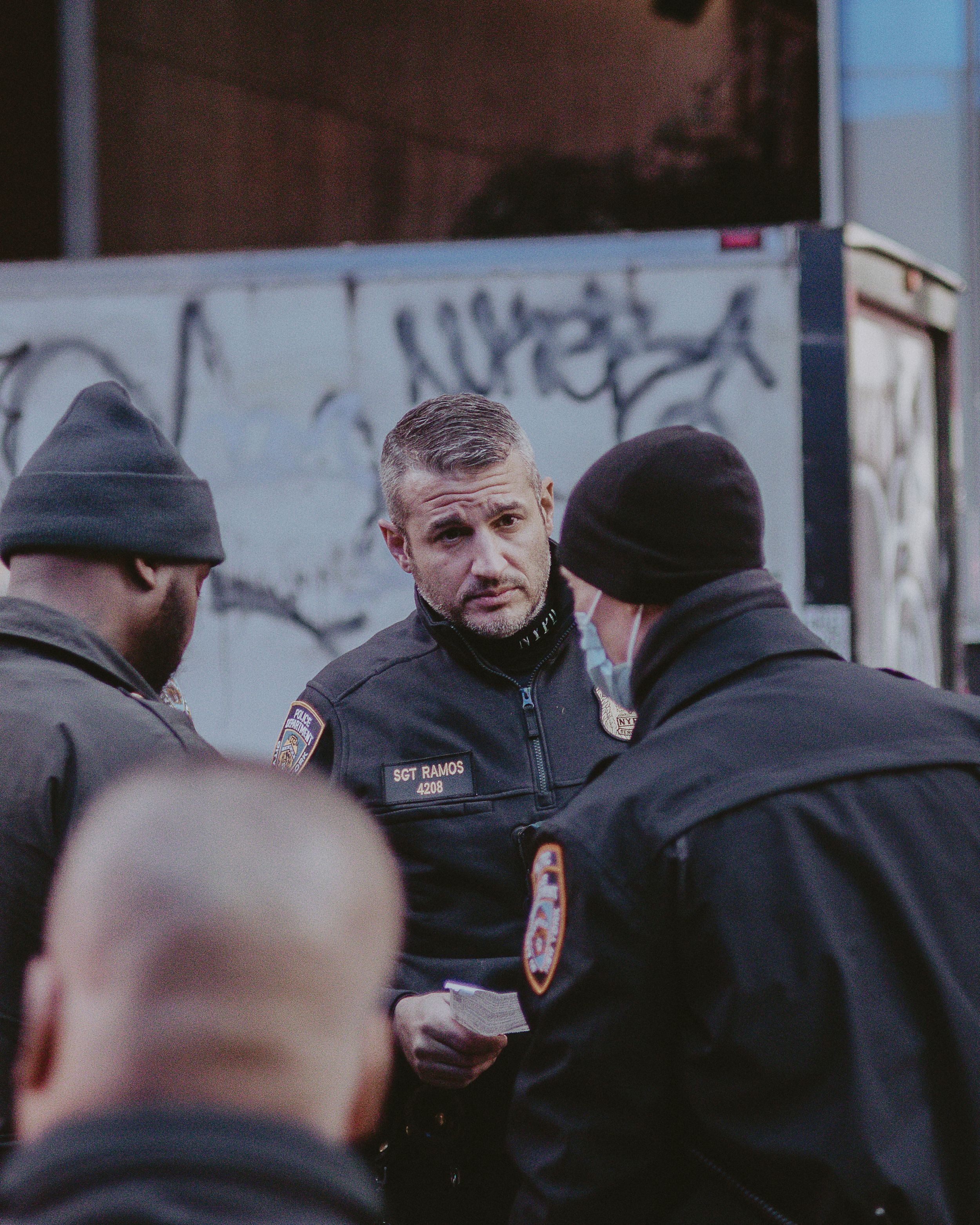 Police officers gather in conversation on a city street at dusk.