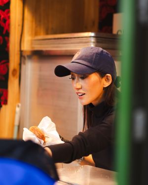 Person in baseball cap serves food at counter.