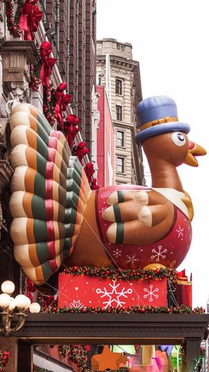 Giant inflatable turkey decoration with blue top hat displayed for Thanksgiving parade.
