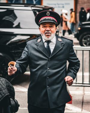 Person in uniform standing near holiday decorations on city street.