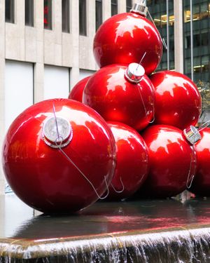 Giant red Christmas ornament decorations displayed outside modern building.