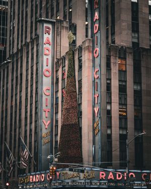 Illuminated Radio City Music Hall sign glows against the dark exterior of the iconic New York City building.
