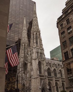 Gothic spires of St. Patrick's Cathedral with American flags flying in New York City.