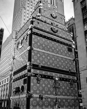 Louis Vuitton monogram pattern on construction barriers against urban architecture.