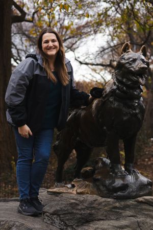 Bronze Balto statue in Central Park with fall foliage in background.