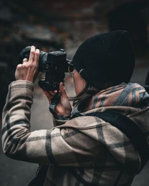 Photographer taking pictures with a camera in dark moody lighting.