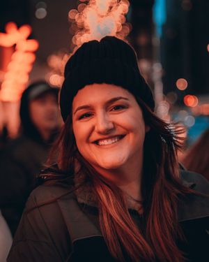 Warm-toned nighttime portrait with orange lighting and beanie hat.