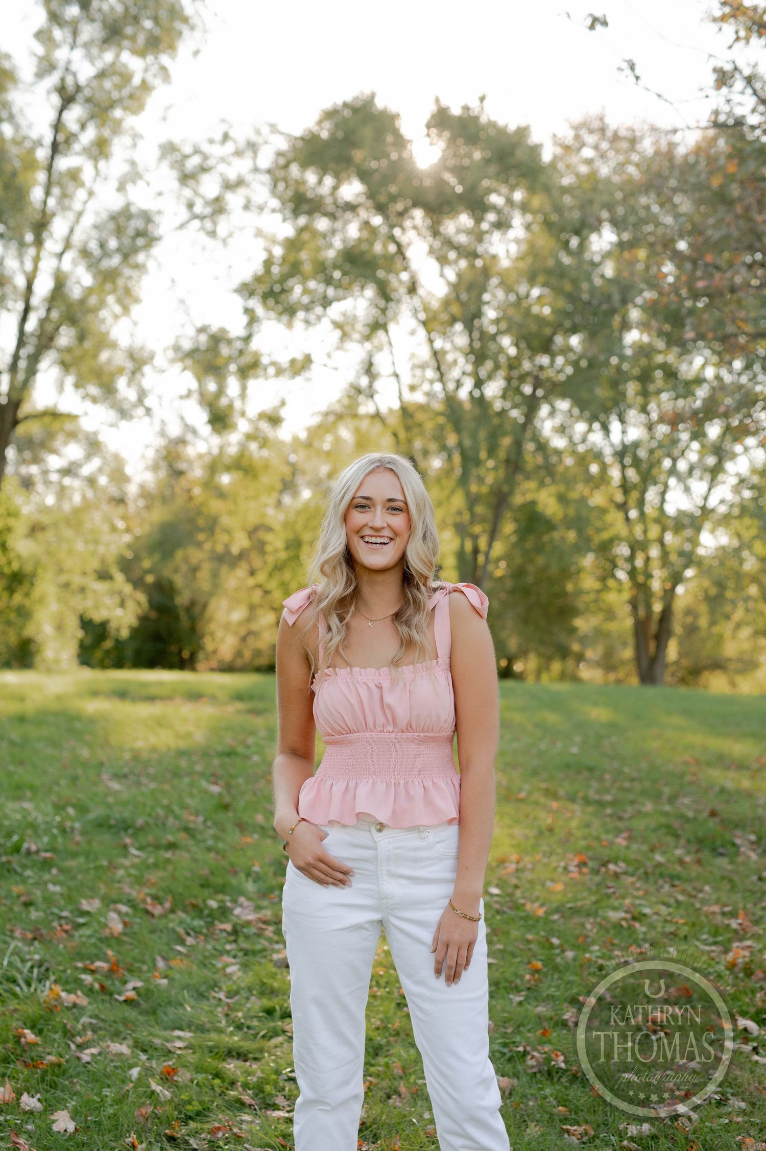 A casual outdoor photo featuring white pants and pink top against a natural backdrop.
