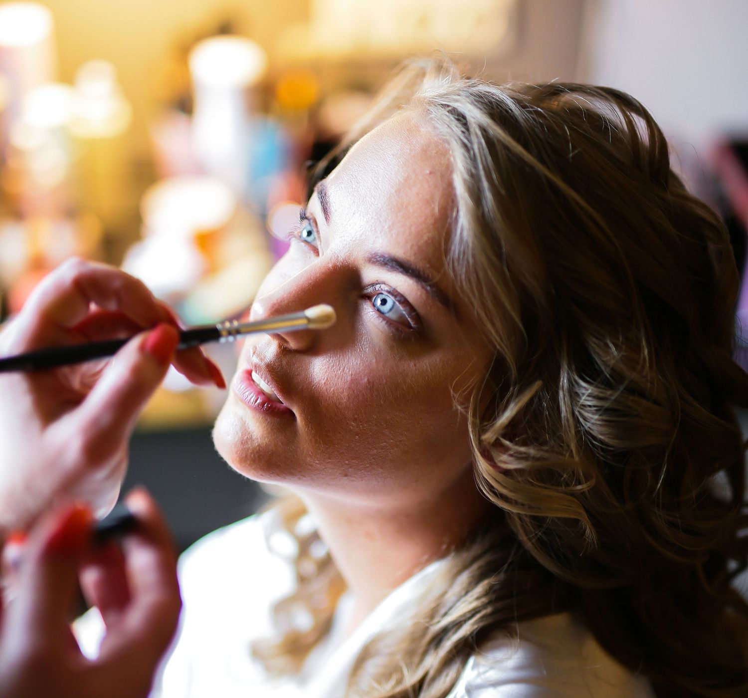 A makeup artist applies lip color to a model during a professional beauty session.