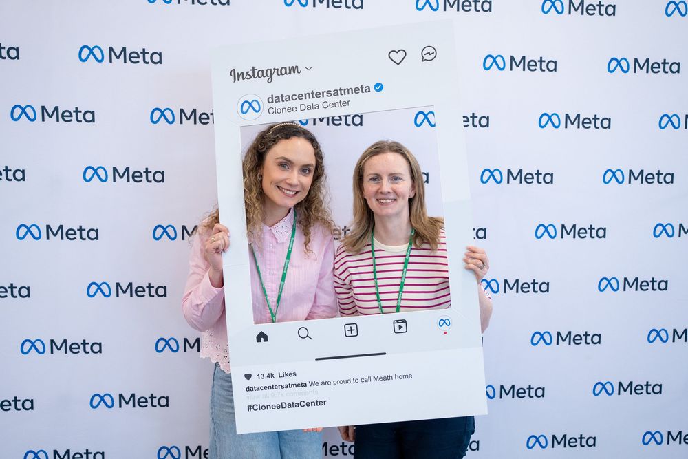 People holding up social media frames and posing in front of a Meta-branded step-and-repeat wall.