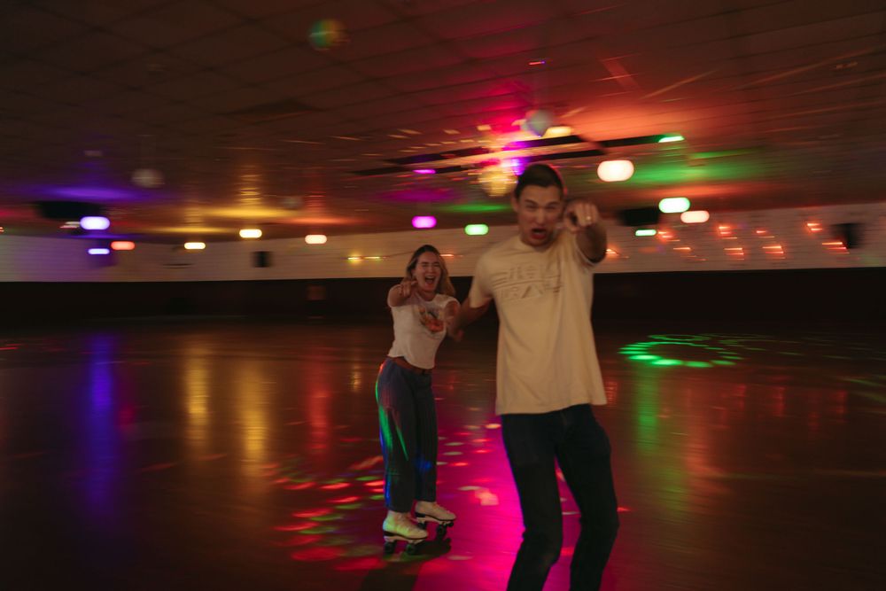 People enjoying roller skating at an indoor rink with colorful disco lights overhead, creating a retro ambiance.