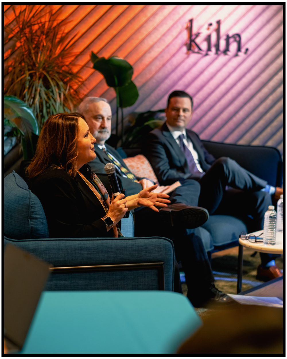 Business discussion taking place in a modern office lounge area with wall signage. Portland event photographer
