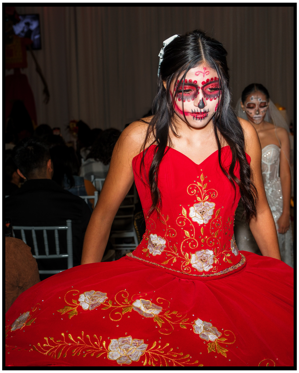 A performer in a red traditional Mexican dress with ornate floral embroidery showcases dramatic Day of the Dead makeup. Portland event photo