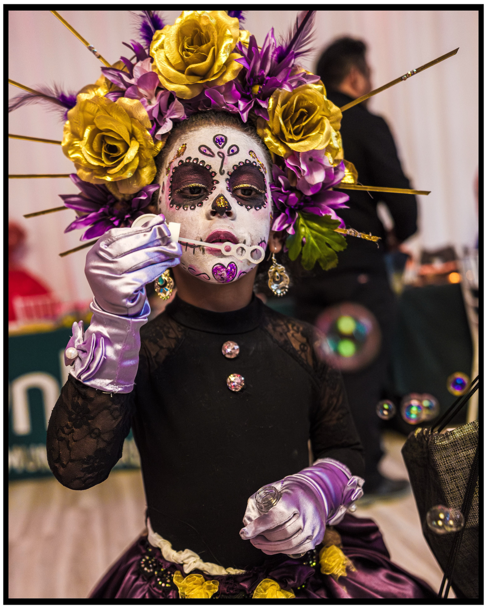 Day of the Dead performer wearing sugar skull makeup and elaborate yellow and purple floral headdress. Portland event photographer