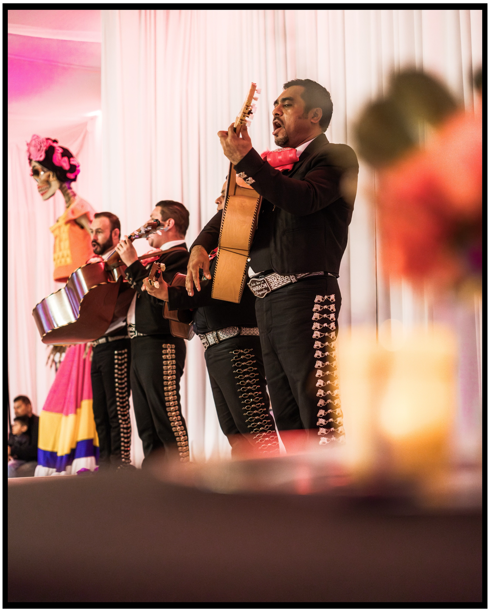 Mariachi band performs in traditional clothing with guitars and instruments on stage. Portland event photographer