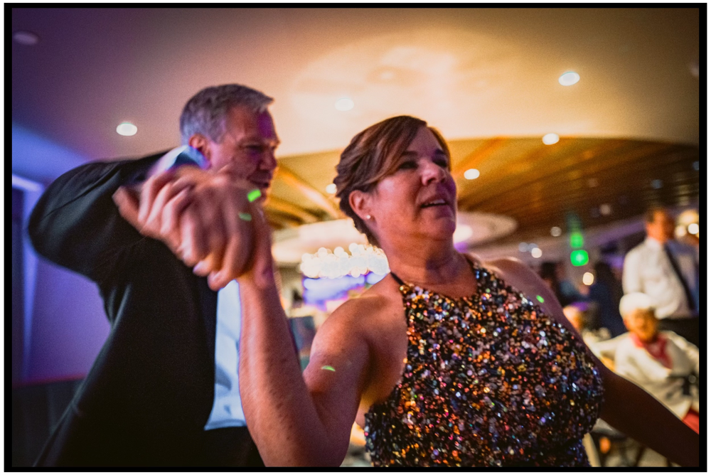 Two people dancing energetically in a dimly lit venue with stage lights in the background. Portland event photographer