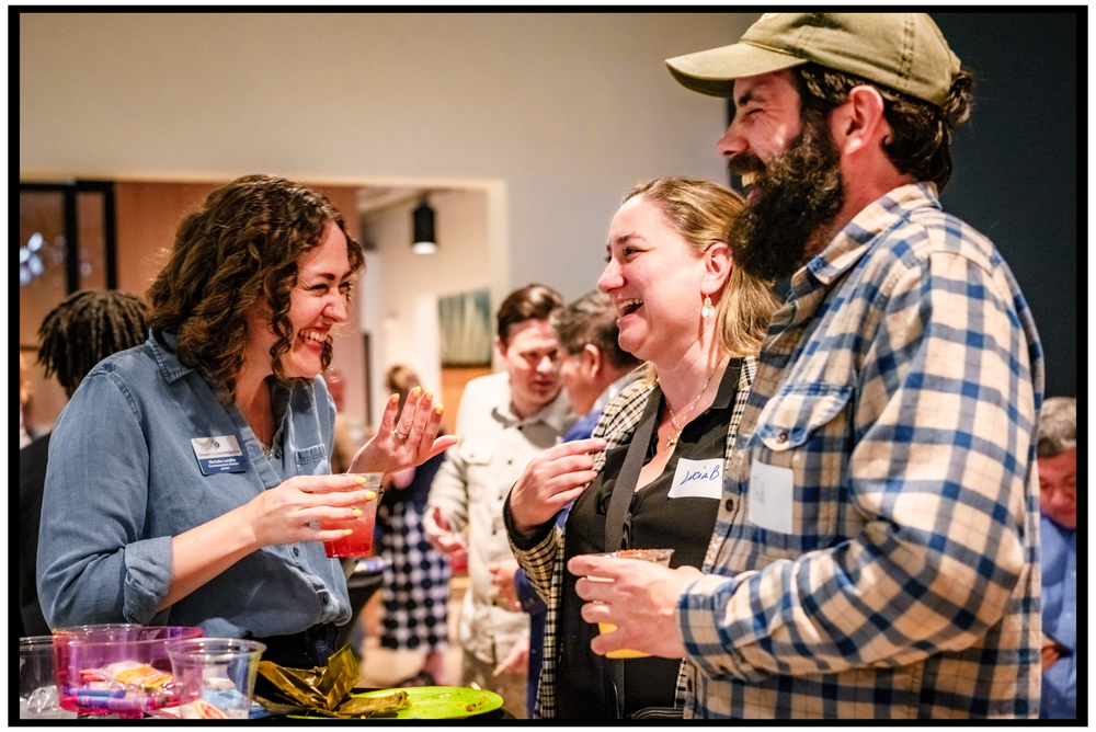 A group of people laughing and socializing at an informal gathering indoor. Portland event photographer