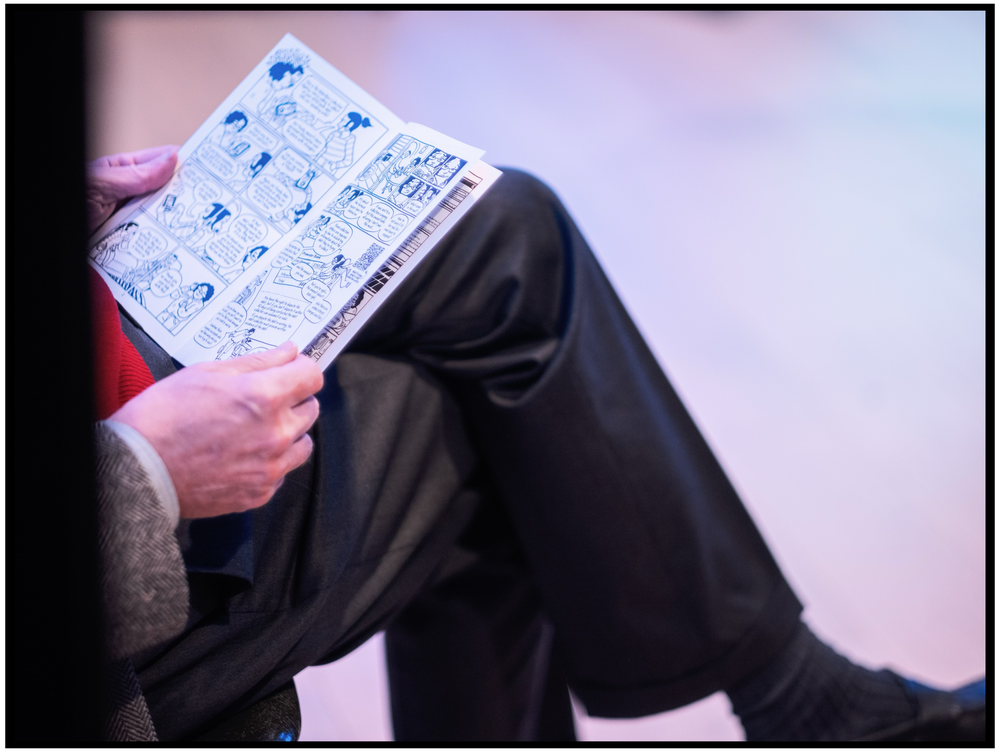 Close-up of hands holding a document with blue illustrated icons. Portland event photographer