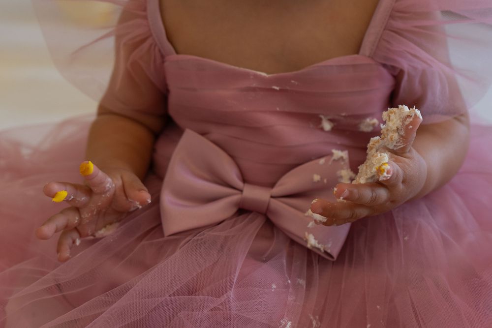 A close-up view of a dusty pink dress with a bow detail and delicate beaded embellishments.