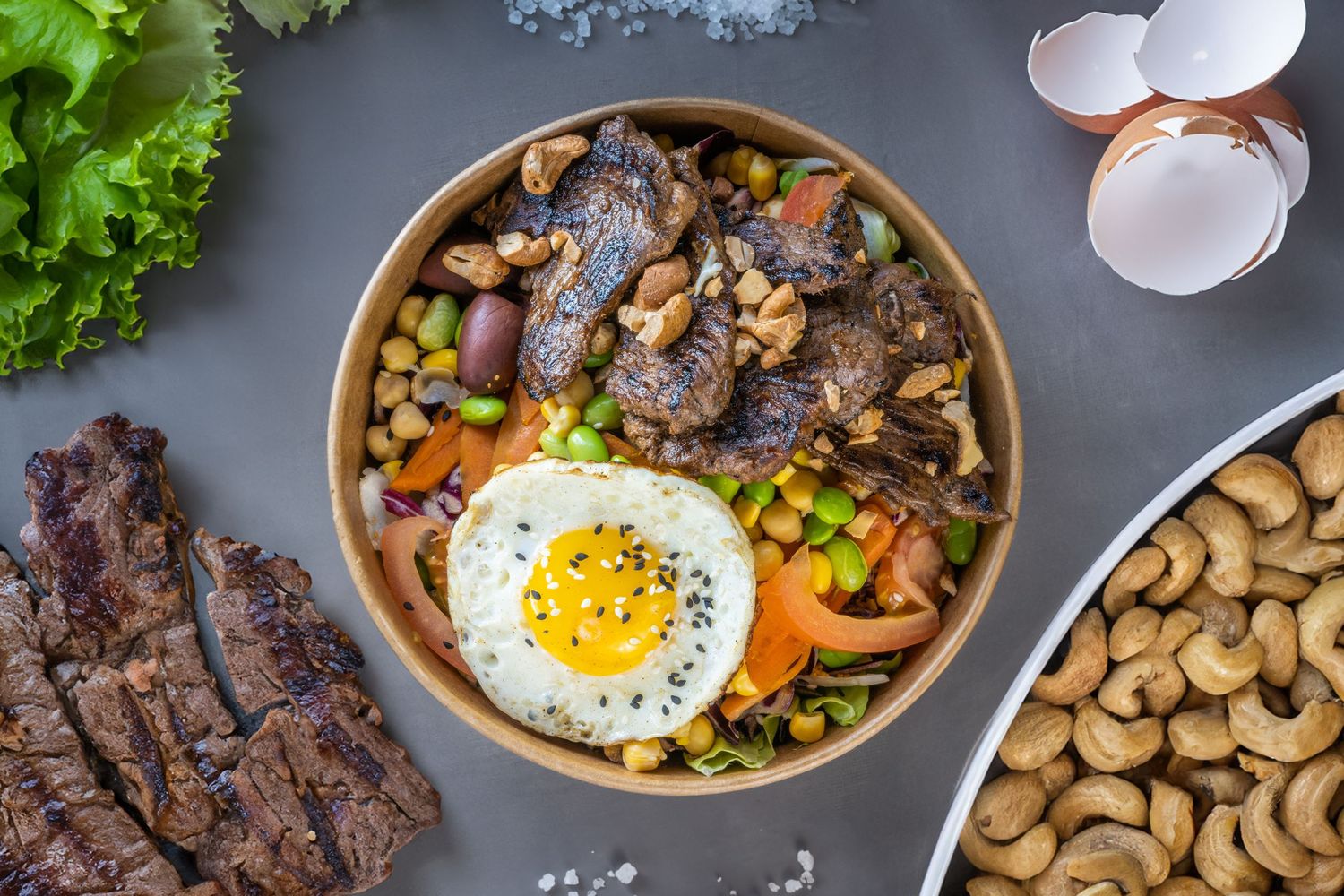 Rustic food preparation scene with fresh ingredients and egg shells on a textured surface.