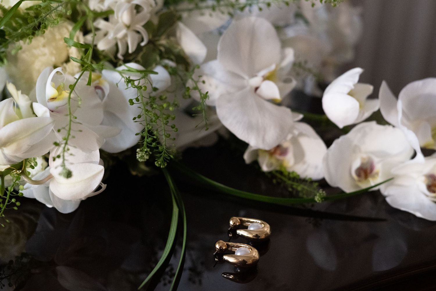 Elegant wedding rings displayed among white orchids and delicate floral arrangements.