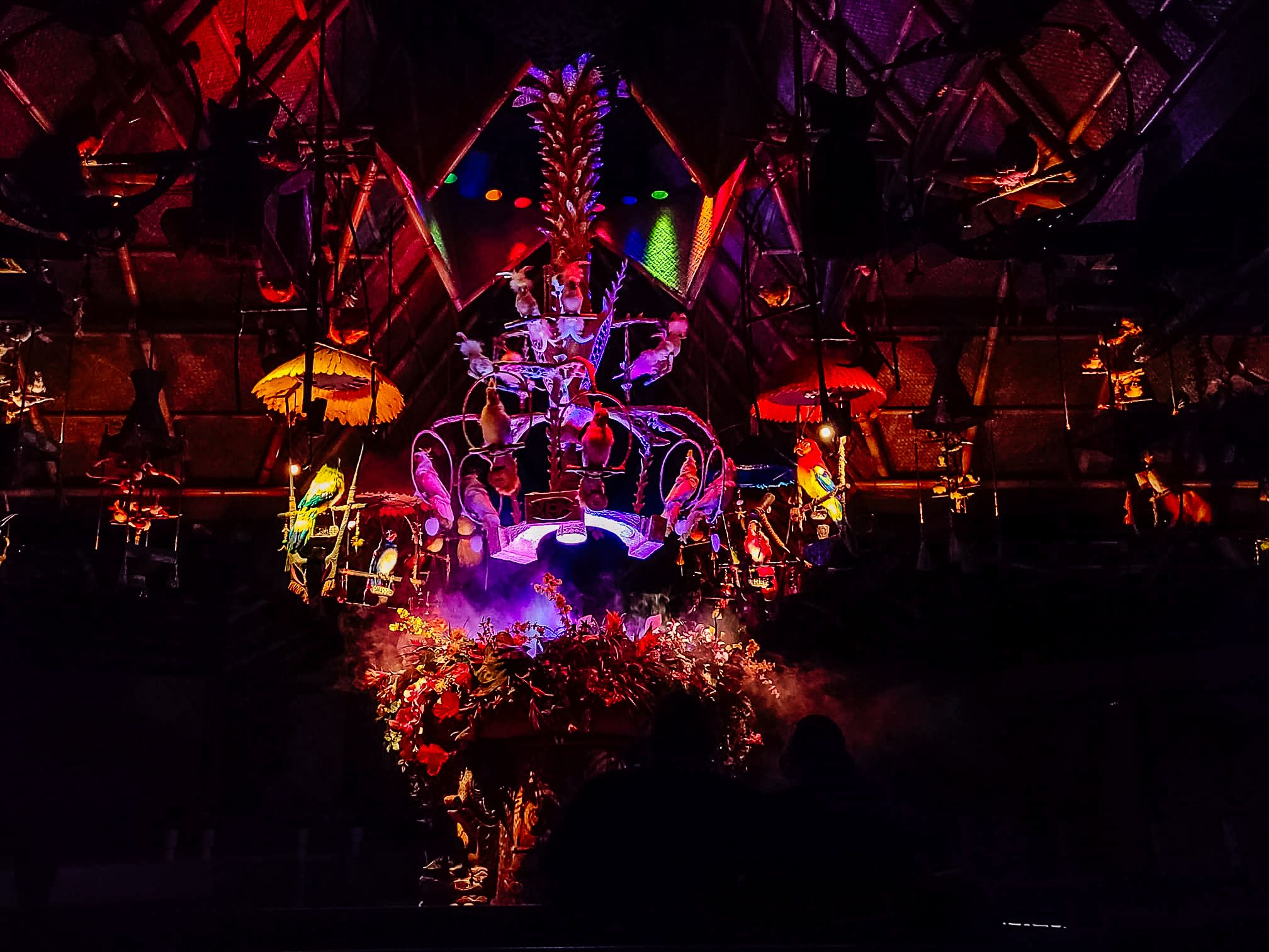Vibrant nighttime theme park attraction with neon purple lighting and red glowing effects in a dark theatrical setting.