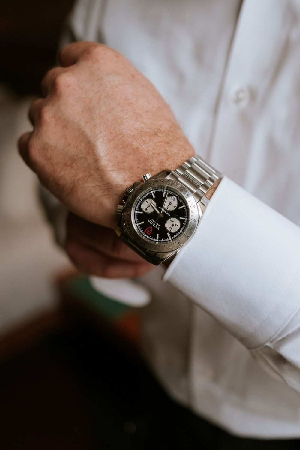Silver chronograph watch on white dress shirt sleeve.