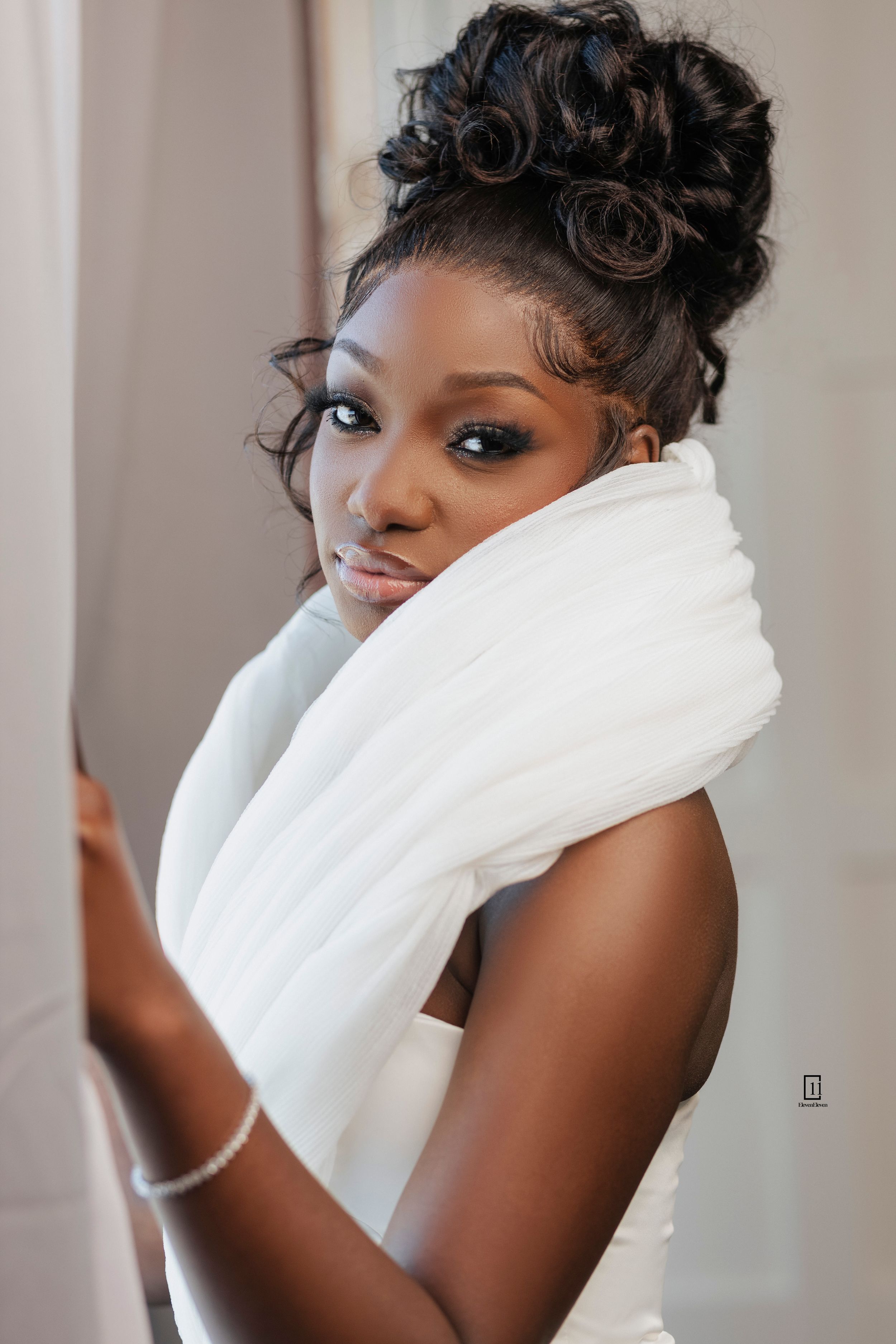 Beautiful bridal portrait featuring an elegant updo hairstyle and white fabric draped across shoulders.