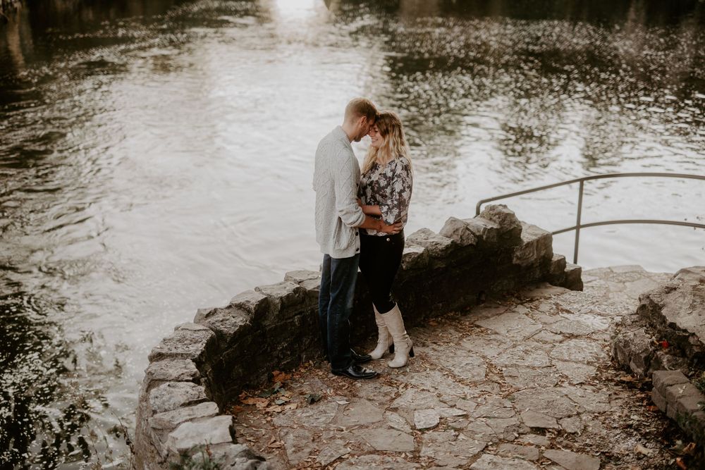 couple with foreheads touching on a stone overlook with the Fergus river in the background