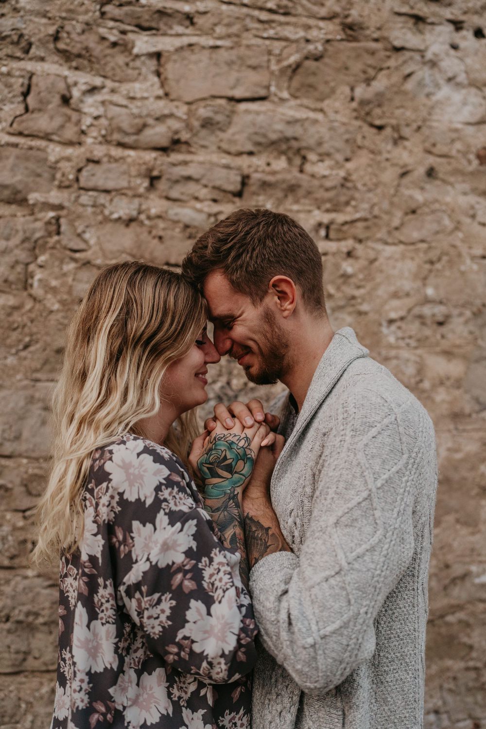 close up of a couple holding hands between themselves huddled in close against a stone wall
