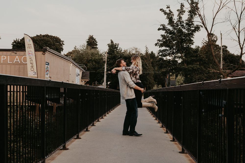 Man lifting and twirling his fiancé on the bridge near a marketplace